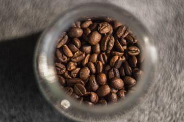 Brown coffee grain in a jar on grey background