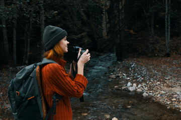 woman with a camera near a pond in the mountains on nature and trees forest landscape