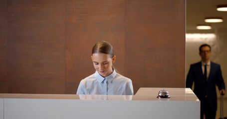 Young businessman with suitcase signing out of hotel 