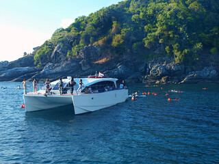 Travel by sea, excursion tourism, yacht cruise. Yacht at sea anchored near rocky coast of island....