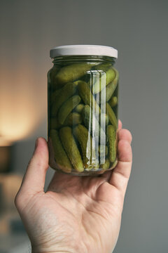 hand holding small glass jar full of pickles