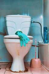 Rubber glove on the lid of an old dirty toilet bowl