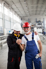 Portrait of workers in factory. Colleagues with helmet working in factory.