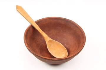 Rustic old traditional kitchen utensils in the form of a clay plate or bowl on a white background. Empty vintage tableware. The spoon is in a ceramic bowl.