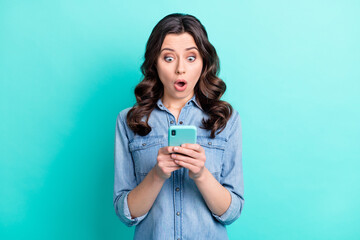 Photo of young girl amazed shocked look read browse fake news cellphone isolated over turquoise...