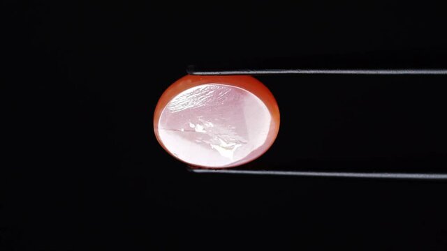 natural moonstone gemstone in tweezer on the turn table
