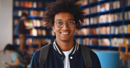 Portrait of afro-american male student smiling at camera in campus library
