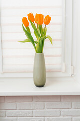 yellow tulips in a vase on the windowsill