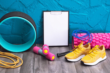 Fototapeta premium yellow sneakers, dumbbells, jump rope, measurement tape, note board and massage rollers