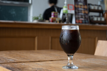 Black iced coffee glass on wooden floor