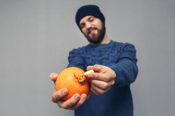 angry bearded man inserts into suppository in orange, concept of hemorrhoids or proctological...