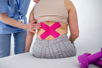 Chiropractor applying three kinesiology tapes. Chiropractor applying two kinesiology tapes to the...