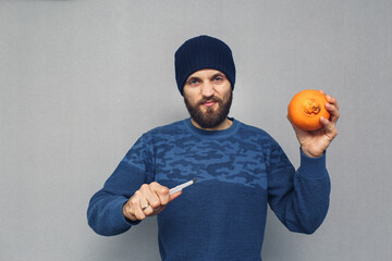 angry bearded man wants to cut out a large navel of an orange with a scalpel, the concept of...