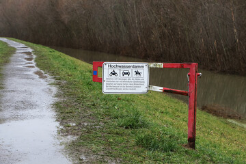 Absperrschranke mit Schrifttafel auf einem Hochwasserdamm