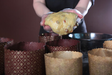 The finished dough for cakes is laid out in forms. Baking cakes for the Easter holiday.An unrecognizable person holds a dough filled with raisins in his hands. A copy of the space.