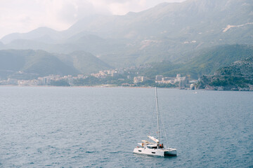 White sailing yacht floats on the sea against the background of the city in the mountains