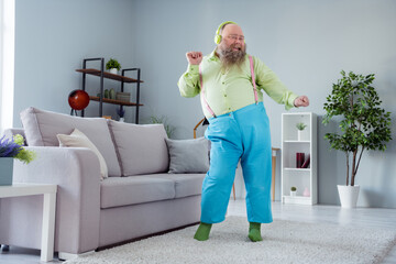 Photo of cute charming big belly man wear green shirt headphones dancing smiling indoors house room