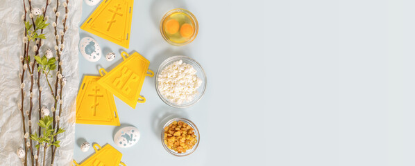 Palm Sunday. Preparation for the Orthodox Easter. Holliday horizontal banner with ingredients for making easter cakes and decorating eggs with palm twigs on a blue background with copy space. Flat lay