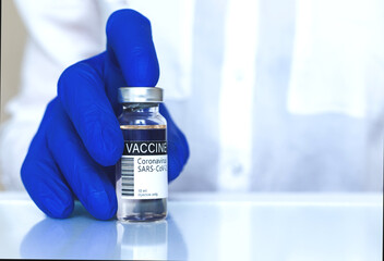 Doctor in a lab presenting coronavirus vaccine, vial with label close-up, healthcare and cure...