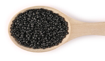 Black beluga lentils in wooden spoon isolated on white background, top view