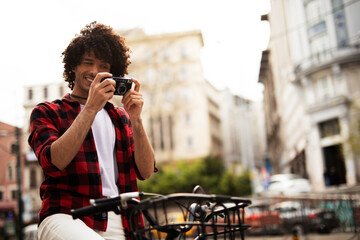 Fototapeta premium Young man traveling with camera. Handsome man traveling around the city.