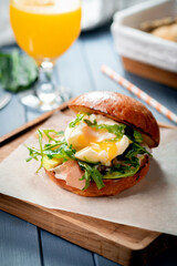 Burger with arugula, jamon and poached egg, with fresh avocado close-up, healthy fast food.