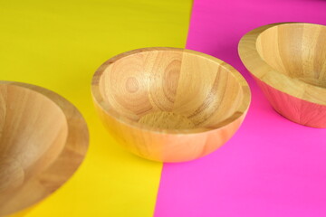 three wooden bowl on beatiful bright pink and yellow background topview