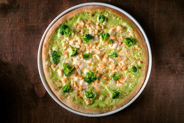 Pizza with broccoli, mozzarella and pesto sauce. Traditional Italian baked pizza on a wooden background