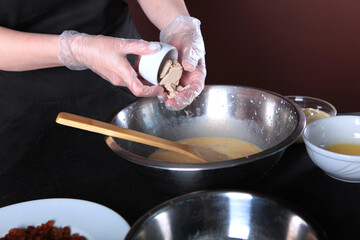 Preparation of dough for cakes. In the hands of the pastry chef yeast. Yeast is added to warm milk. Baking for the holiday. An unrecognizable person.