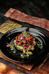 salad with veal, grilled vegetables, sprouts and lettuce leaves on a black plate on a metal copper background. close up