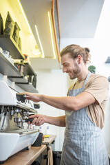 Naklejka na ściany i meble Young adult man busy near coffee machine
