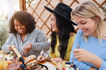 Young multiracial friends having brunch outdoors in restaurant - Focus on asian girl face