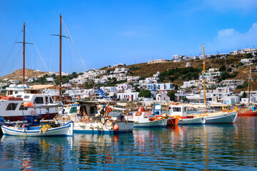 Fototapeta na wymiar Beautiful summer day in typical marina of Greek island Mykonos, Greece. Colorful fishing boats moored at jetty. Mediterranean lifestyle, vacations. 