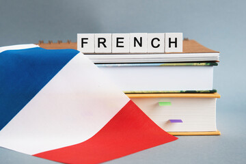 the inscription french on a stack of textbooks, books, exercise books and national flag of France,...