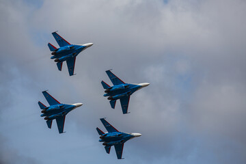 Fototapeta na wymiar four jet planes are flying in a tight formation. dangerous aerobatics are shown at the aviation festival by pilots. military parade of modern fighter planes