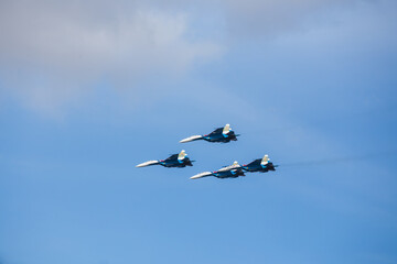 four jet planes are flying in a tight formation. dangerous aerobatics are shown at the aviation festival by pilots. military parade of modern fighter planes
