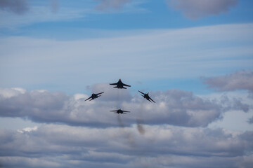four jet planes are flying in a tight formation. dangerous aerobatics are shown at the aviation festival by pilots. military parade of modern fighter planes