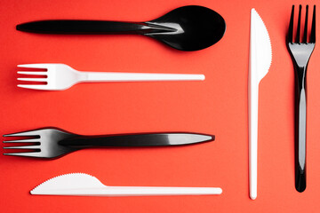 Forks and spoons on red background. Plastic cutlery, ecology, environmental pollution by plastic, disposable tableware, waste recycling concept. copyspace, flat lay