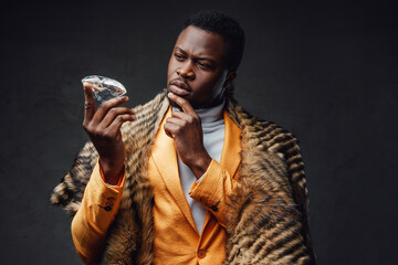 Pensive black man in yellow coat holding diamond