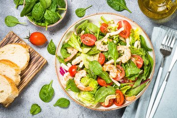 Shrimp salad with green leaves at stone table.
