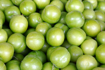 Green plums on the counter of the bazaar close-up, background