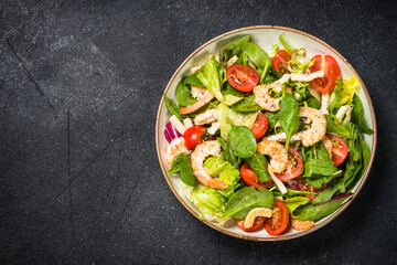 Shrimp salad with green leaves at stone table.