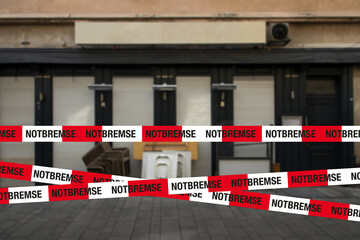 notbremse absperrband mit geschlossener gastronomie im hintergrund