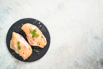 Chicken fillet with spices and herbs at white table.