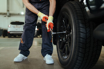 Obraz premium Mechanic changing a wheel and tire of modern car in workshop