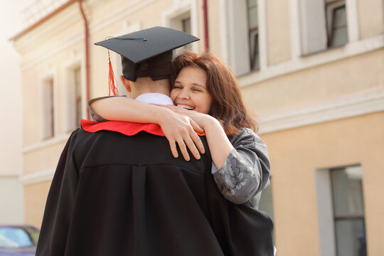 Mother hugs her son student in graduation gown and a square cap after the graduation ceremony
