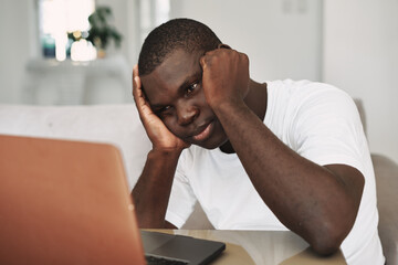 Risen African man with sits at the table with open laptops and looks at the monitor