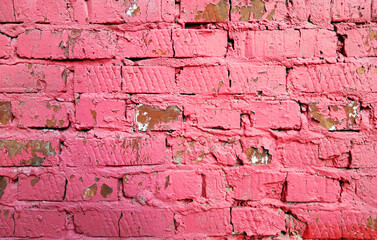 Background of an old wall from bricks painted with red paint. Peeling paint on a brick wall