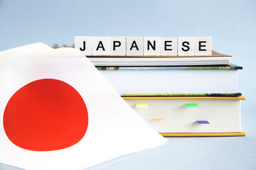 the inscription japanese on a stack of textbooks, books, exercise books and national flag of Japan,...