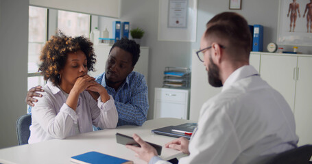 Upset afro-american couple visiting doctor at family planning clinic
